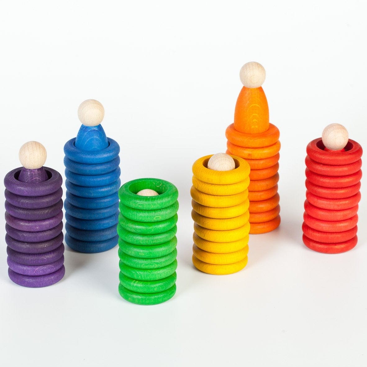 rainbow coloured peg dolls and wooden rings on a white background 