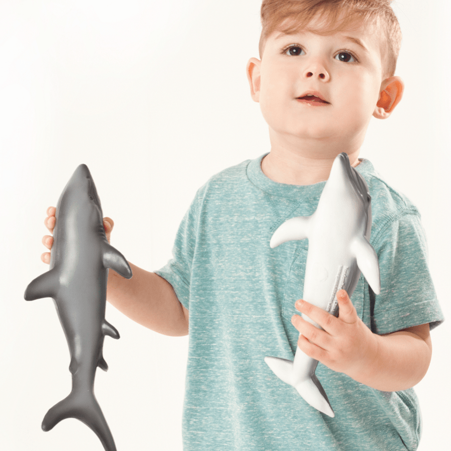 boy holding a rubber shark toy made by green rubber toys for children over 12 months old