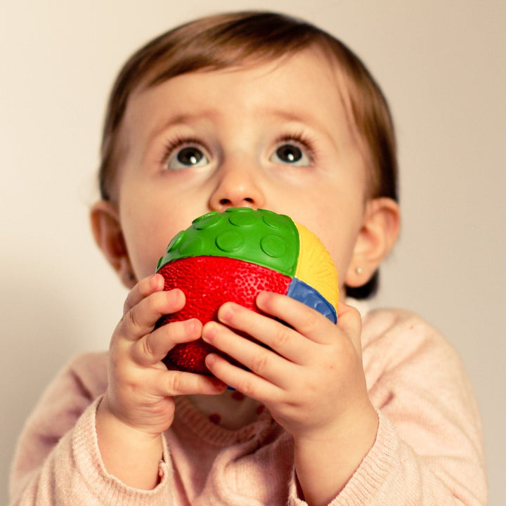 baby grasping a rainbow rubber sensory ball