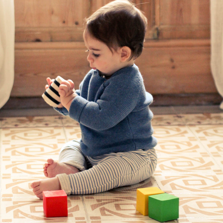 toddler sitting on the floor playing with rubber Geometric sensory Shapes