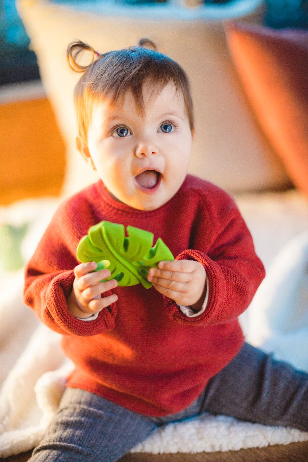 toddler holding a green monstera leaf rubber teether