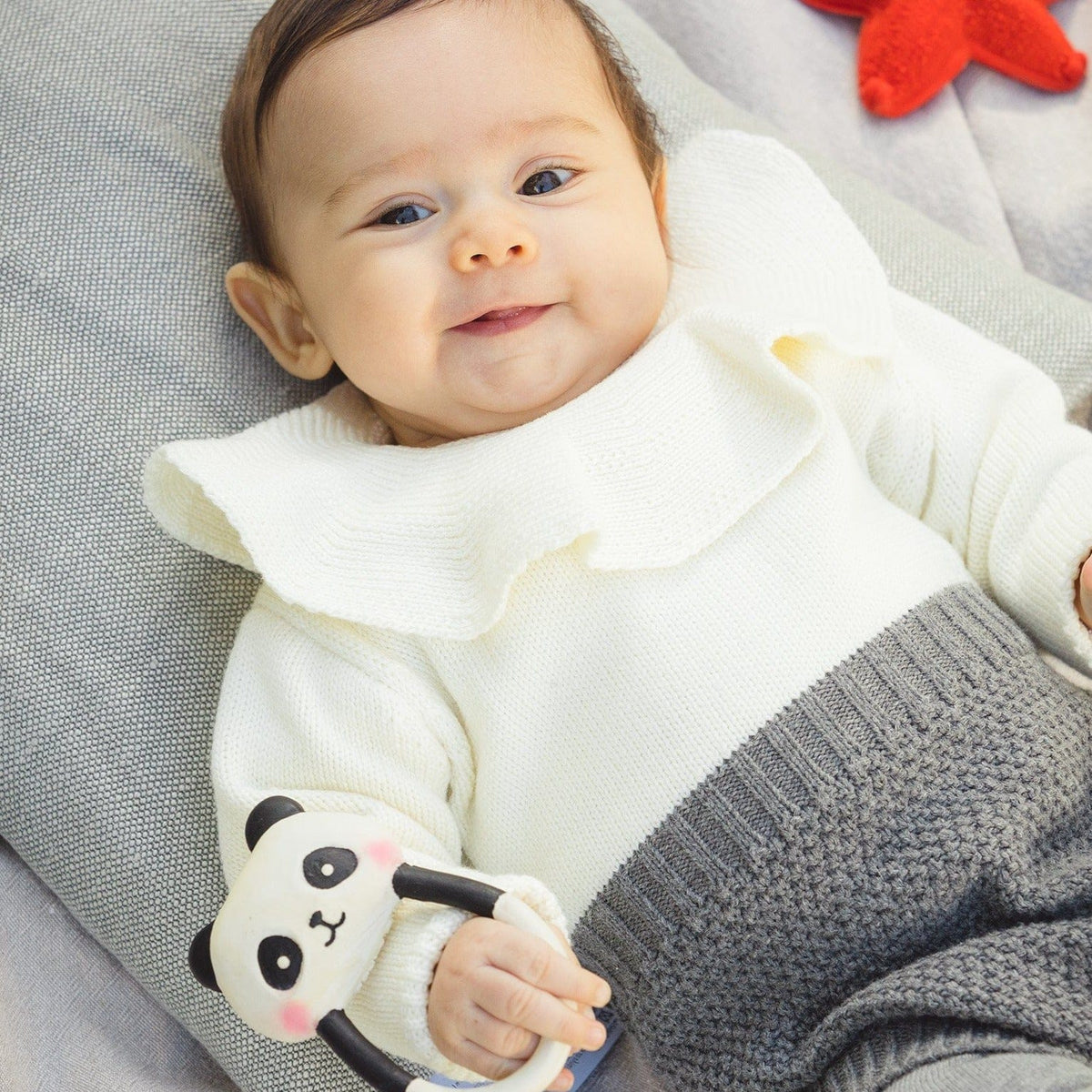 bab grasping a rubber panda teething toy 
