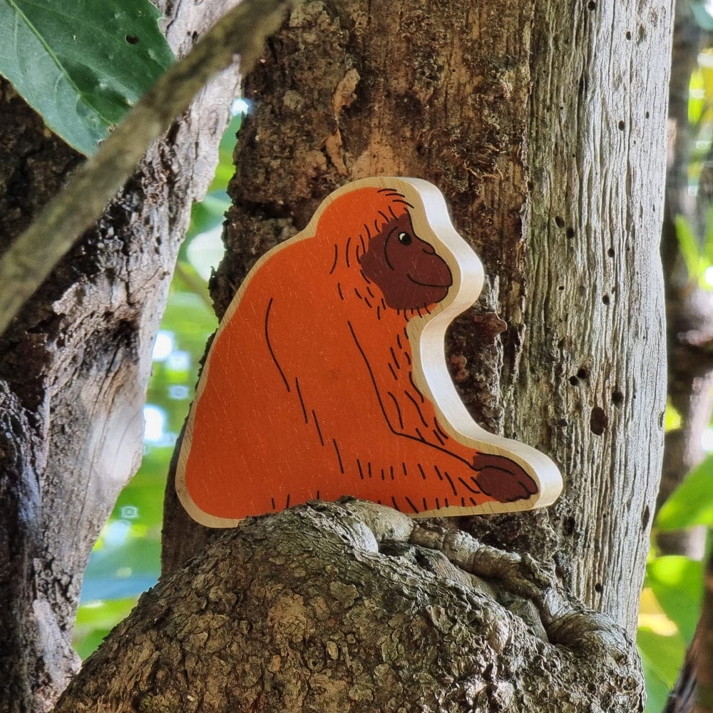 wooden orangutan play figure in and outdor setting perched on a tree branch