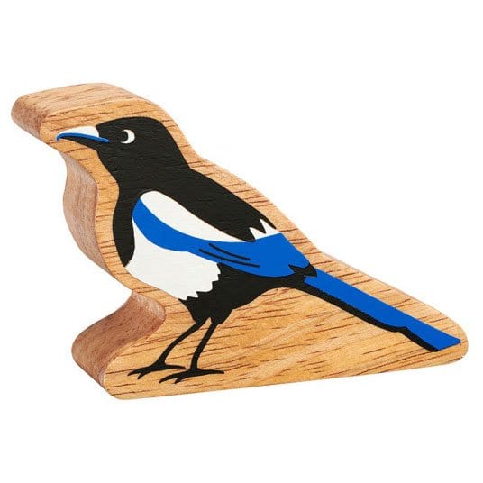 A wooden toy figure of a magpie with black, white, and blue coloring on its body, standing on a natural wood edge.