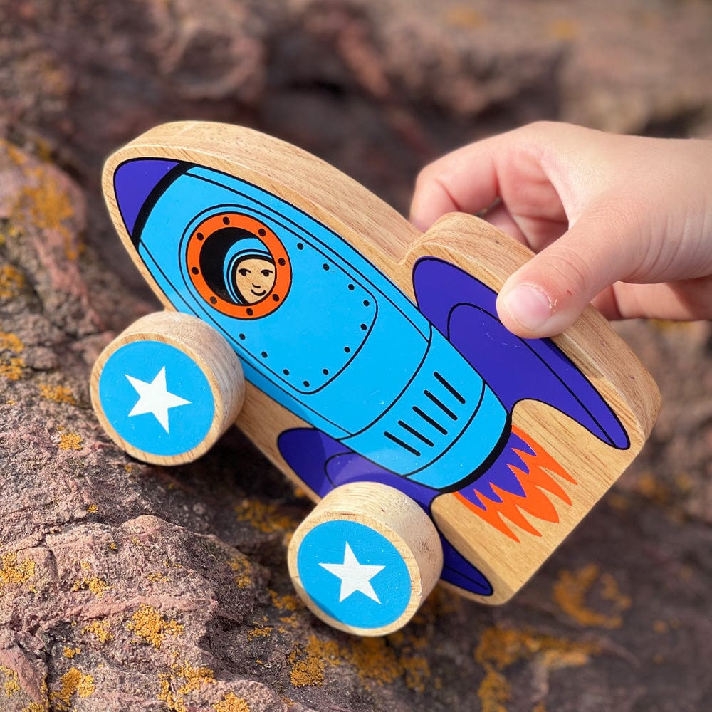 childs hand playing with a blue wooden rocket push along toy