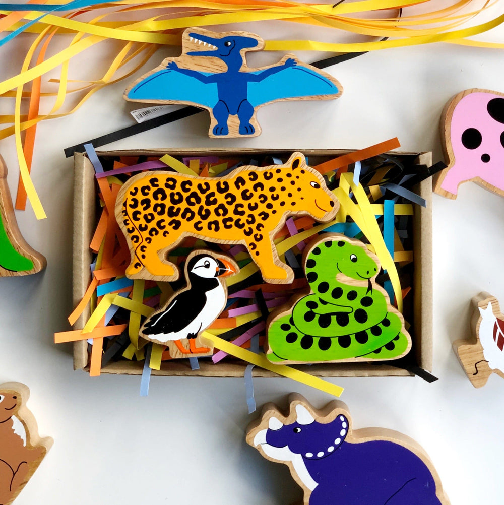 kraft gift box with colourful shredded paper and several Lanka Kade wooden animals - snake, leopard, puffin, dinosaur and pig. For children aged 10 months and over